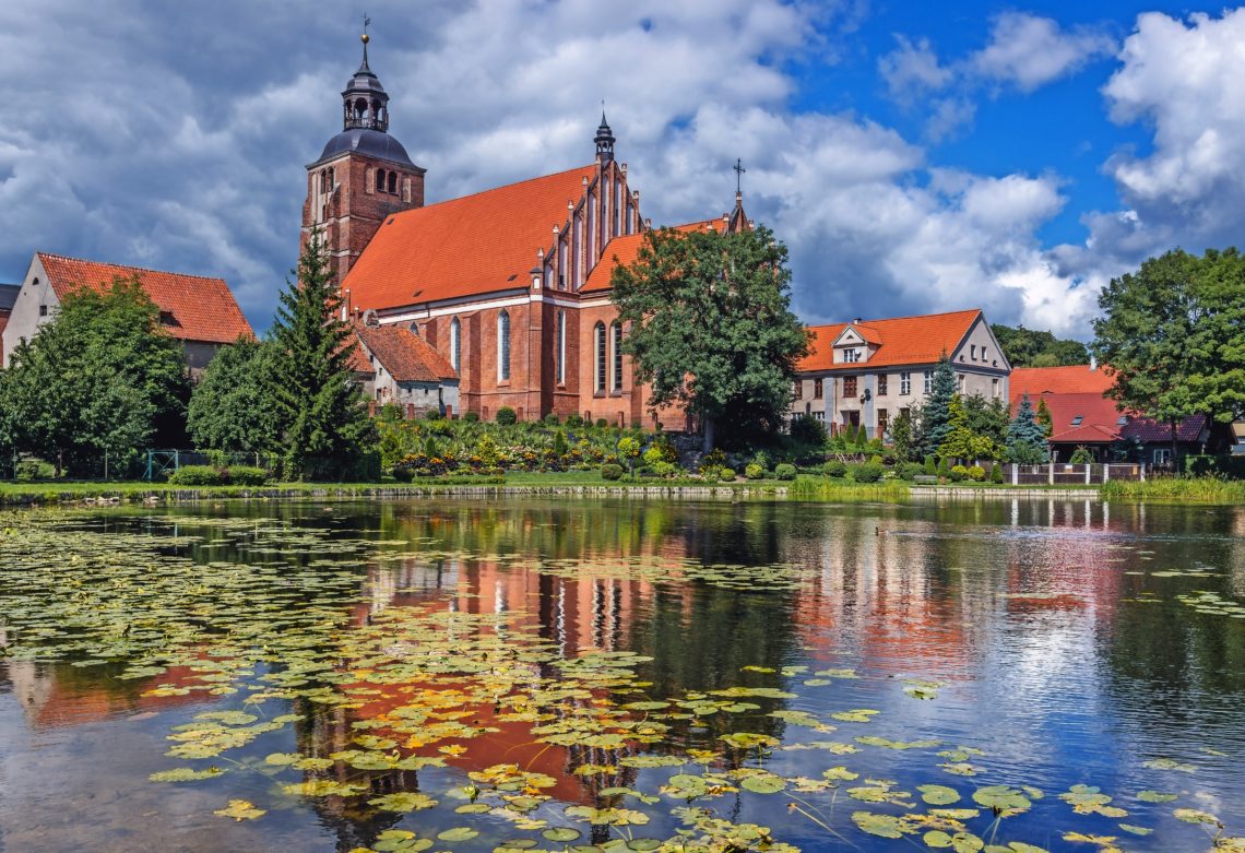 Pond on Pisa River and Saints Anne and Stephen Catholic Church in Barczewo, small city near Olsztyn, Masuria region of Poland