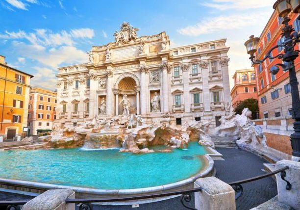 Trevi Fountain in Rome, Italy. Ancient fountain. Roman statues at piazza in old medieval city among traditional italian houses and street lamps. Famous landmark. Touristic destination for vacation.