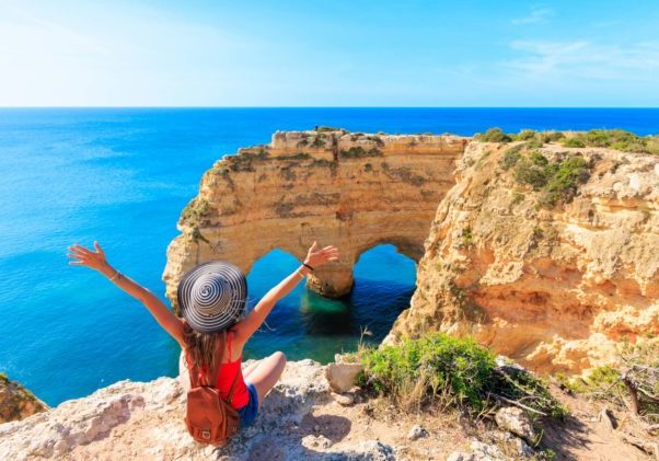 Tour tourism in Algarve- Happy summer holiday, travel in Europe- Happy woman tourist enjoying beautiful view of natural arch in atlantic ocean- Portugal, Carvoeiro